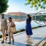 People walking along a lakeside path at Durgam Cheruvu Park with greenery and rocks.