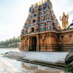 Coastal Hindu temple with tall gopuram towers beside the sea.