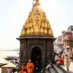 Golden-spired Kashi Vishwanath Temple in Varanasi with pilgrims around the entrance.